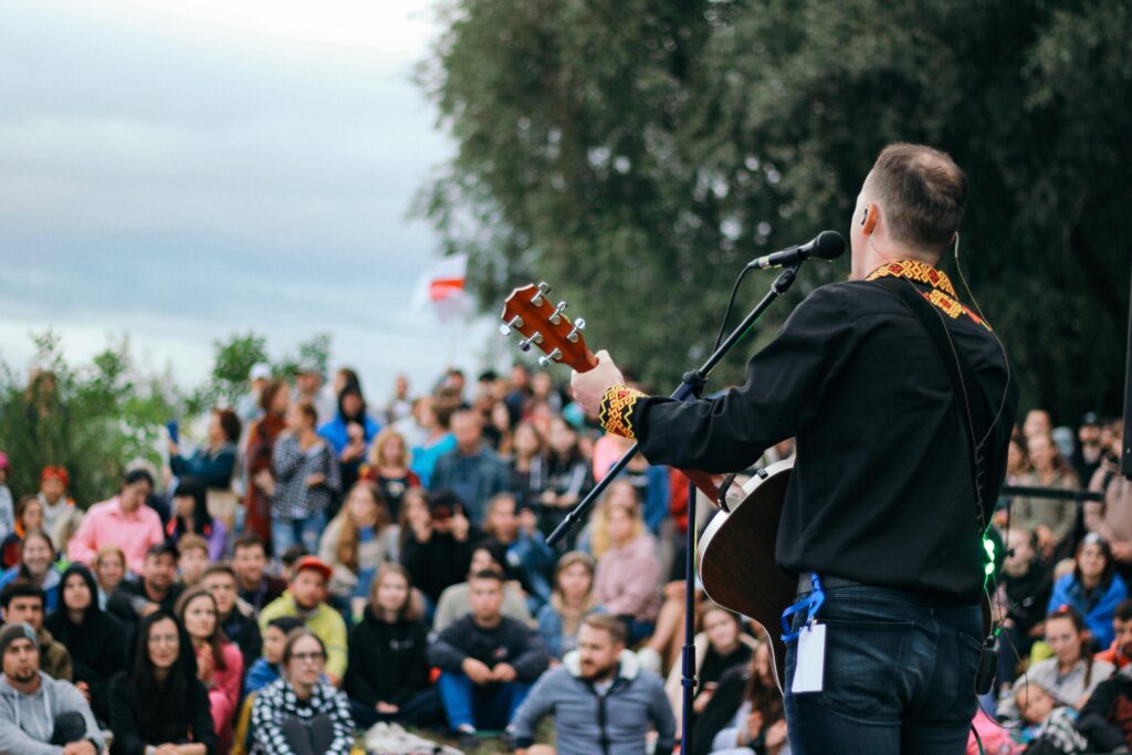 A lively outdoor concert featuring a man playing guitar with an engaged audience in attendance.